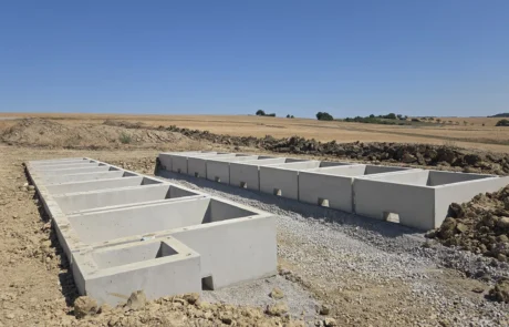 Betonfertigteil-Fundamente in zwei Reihen auf Schotterbett für die Speicheranlagen, Baufeld Solarpark Mulfingen, Baden-Württemberg