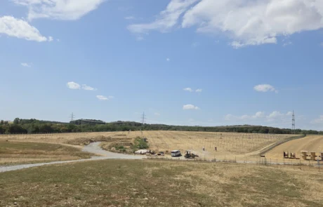 Weitwinkelaufnahme Baufeld Solarpark Mulfingen mit Zufahrt, Lagerplatz, Baufahrzeugen und gerammten Pfostenreihen am Hang, Hohenlohekreis