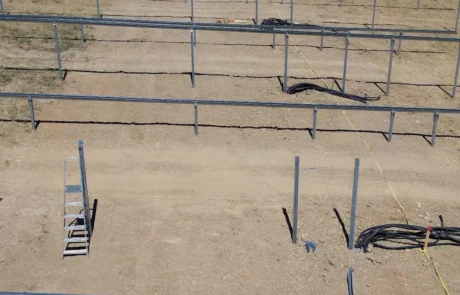 Montierte Unterkonstruktion mit Längs- und Querträgern und ausgelegten DC-Kabeln, Ortschaft im Hintergrund, Solarpark Mulfingen I