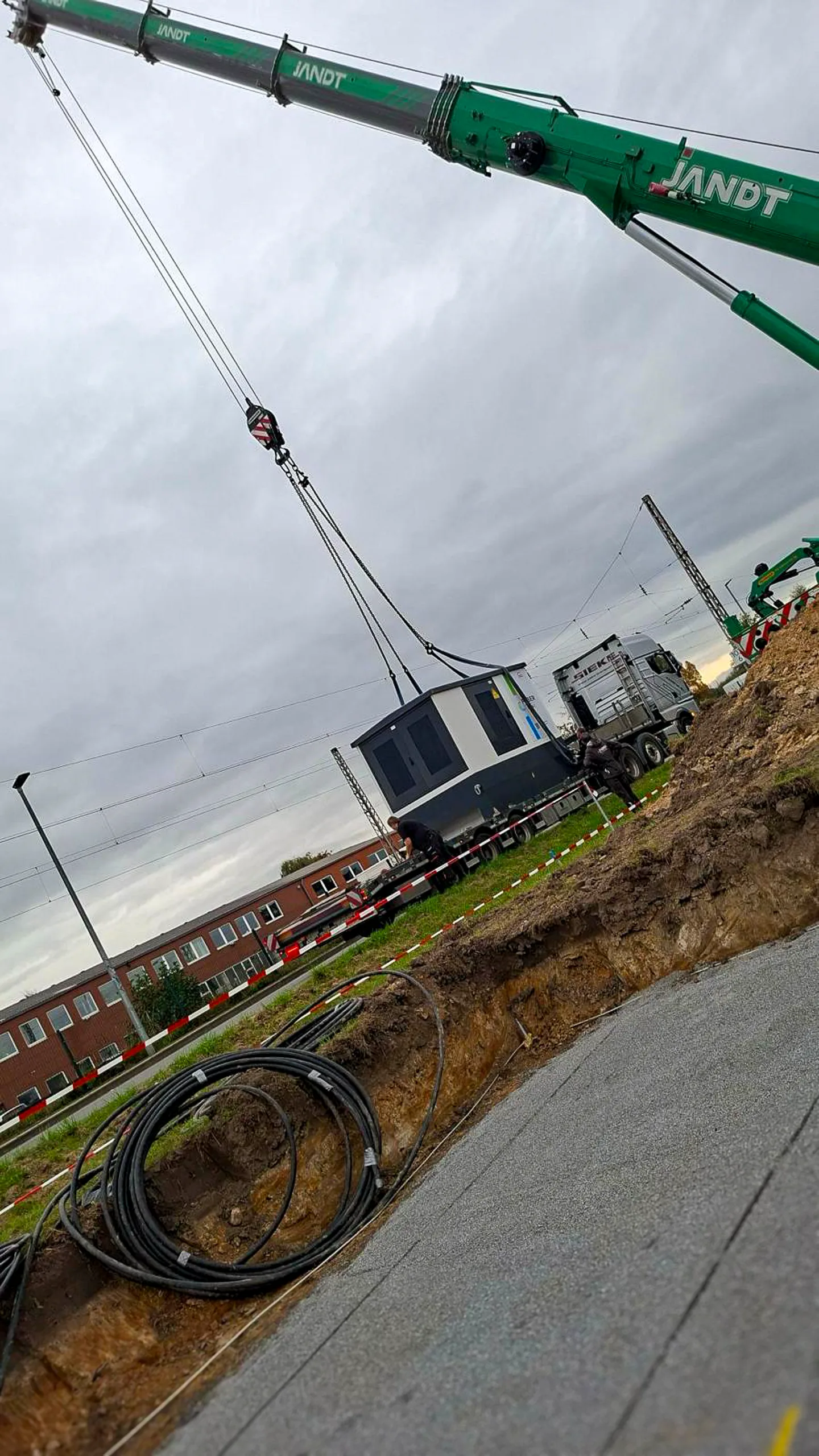 groetsch-partner-pv-roedinghausen-3200kwp–11 Trafostation hängt am Kran über dem vorbereiteten Fundament in Rödinghausen